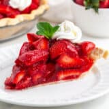 Slice of fresh strawberry pie on a white plate.