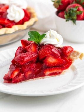 Slice of fresh strawberry pie on a white plate.