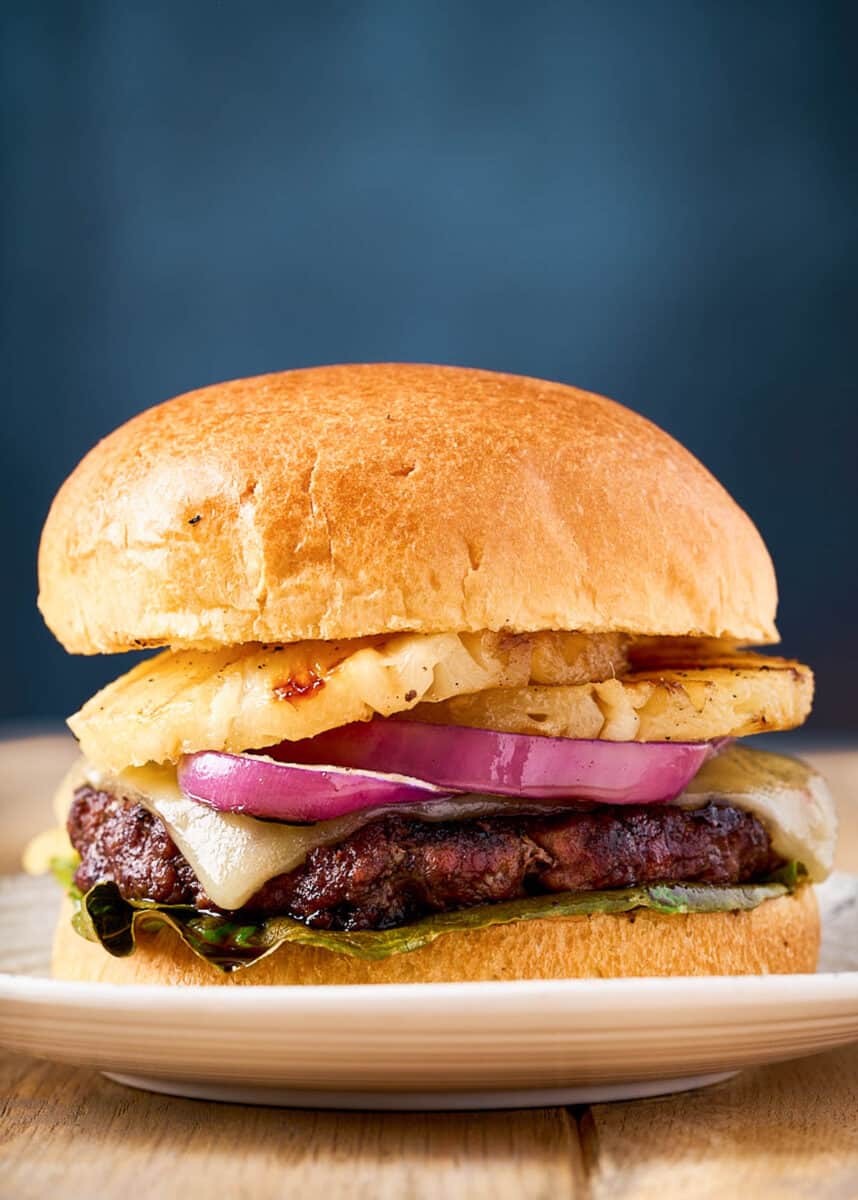 Teriyaki burger with onion and pineapple on plate.