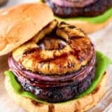 open teriyaki burger with onion and pineapple on top on board