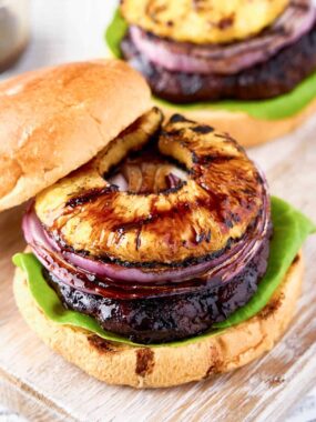 open teriyaki burger with onion and pineapple on top on board