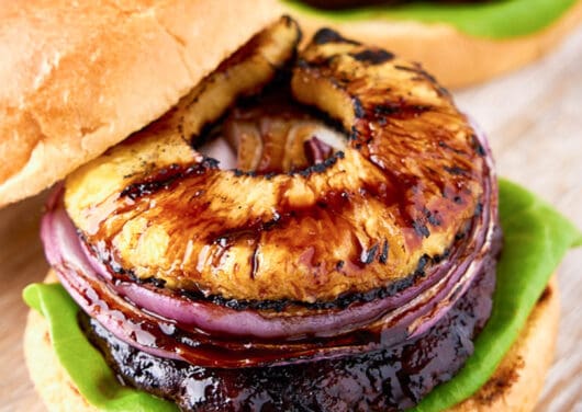open teriyaki burger with onion and pineapple on top on board