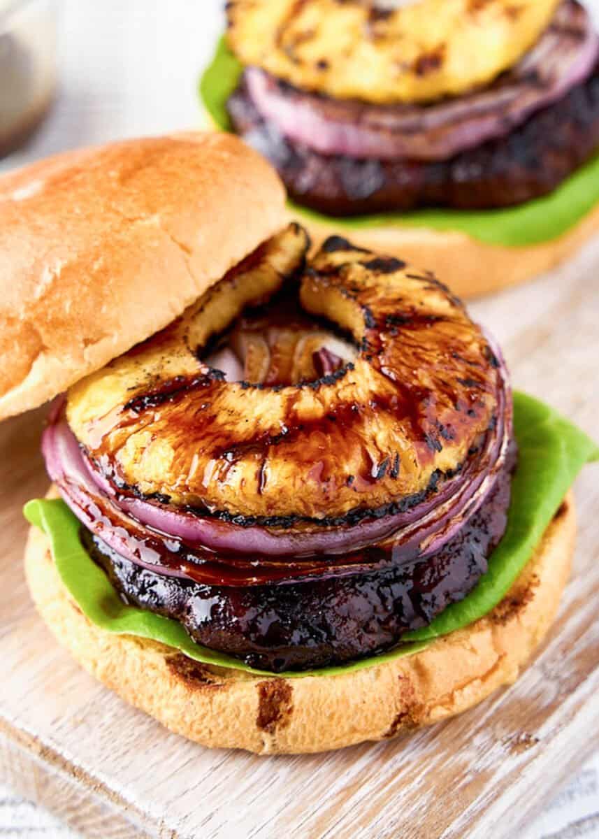 Open teriyaki burger with onion and pineapple on top on board.