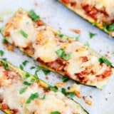 Zucchini boat with cheese and parsley on top.