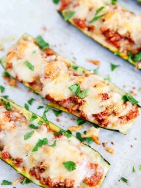 Zucchini boat with cheese and parsley on top.