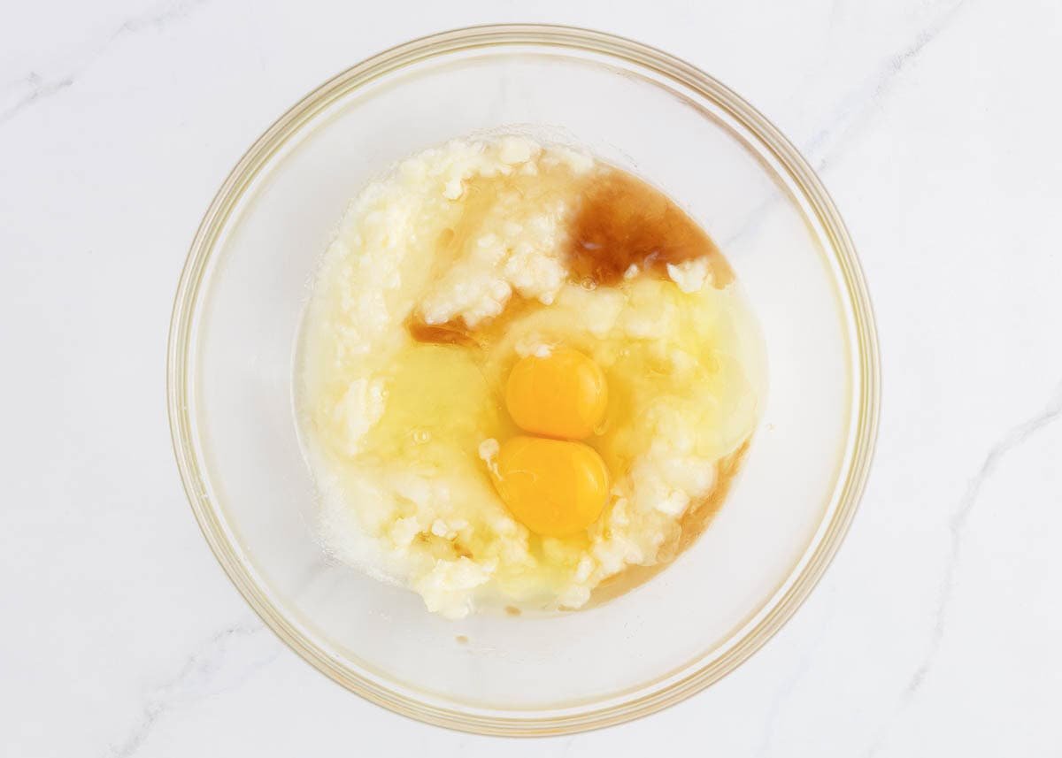 Coconut cupcake wet ingredients with eggs, coconut milk, and extracts in a mixing bowl.