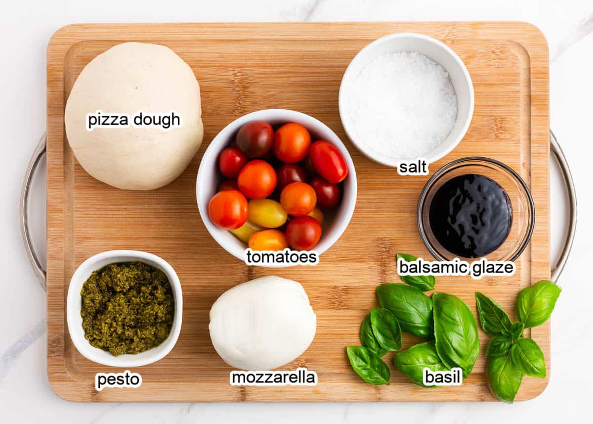 Caprese pizza ingredients on wooden cutting board.