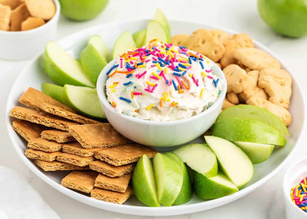 Funfetti dip on white plate with crackers and apples.