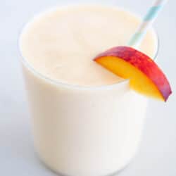 Peach smoothie in cup with straw.