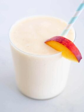 Peach smoothie in cup with straw.