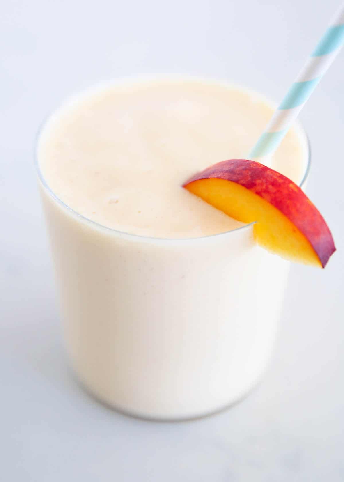 Peach smoothie in cup with straw.