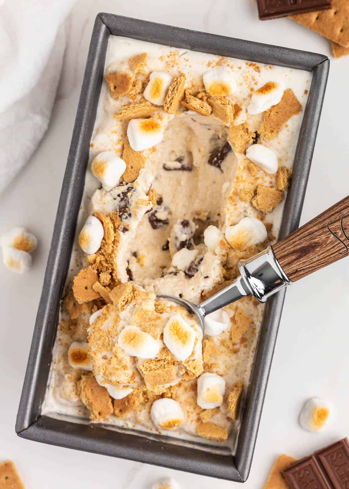 Creamy s’mores ice cream in a loaf pan with fudge and graham cracker swirls.
