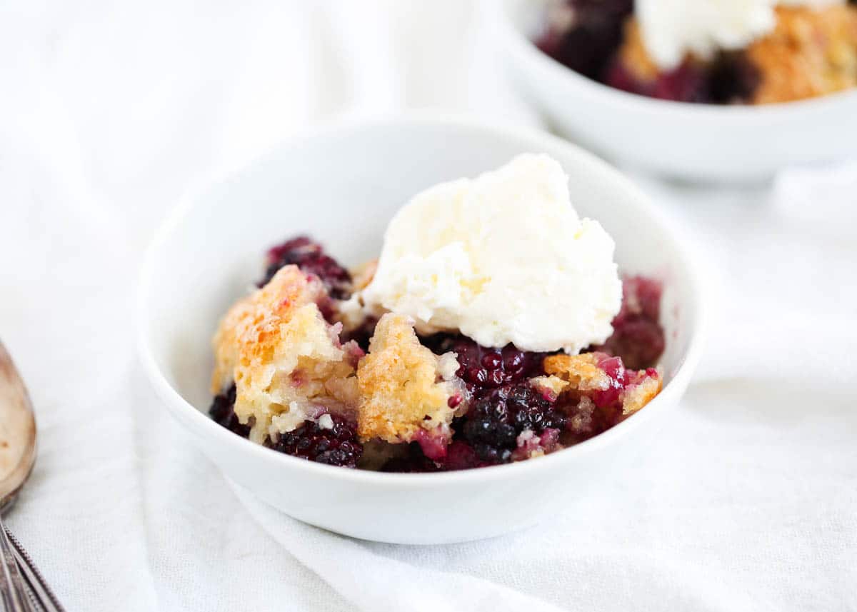 Blackberry cobbler and ice cream in a white bowl.