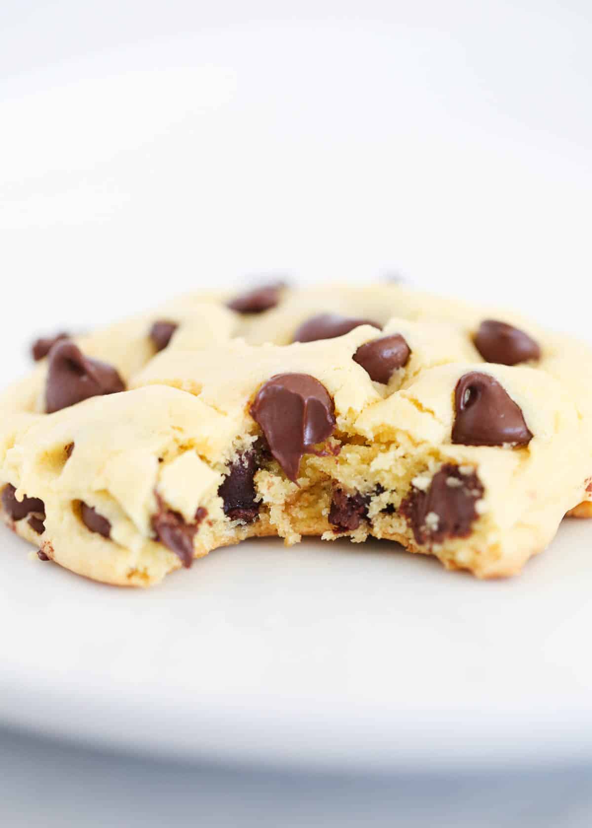 Cake mix chocolate chip cookies are chewy and delicious, and take quick and easy cookie recipes to another level using just a boxed mix, oil, eggs, and loads of chocolate chips! Bite taken from chocolate chip cake mix cookie to show gooey soft texture.