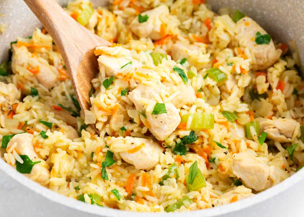 Chicken and rice in a pot with wooden spoon.