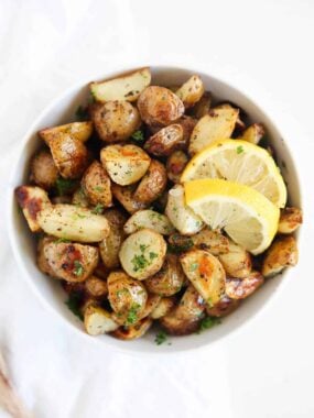 Greek potatoes in a white bowl with lemons.