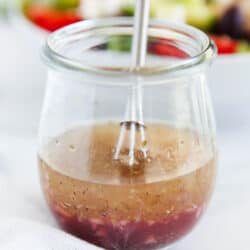 Whisking Greek salad dressing in a glass jar.