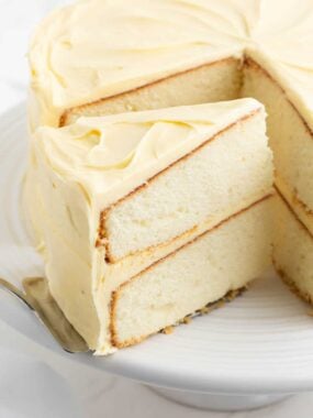 Serving a slice of homemade vanilla cake with a cake server.
