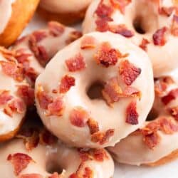 Maple bacon donuts stacked on a plate.