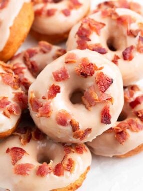 Maple bacon donuts stacked on a plate.