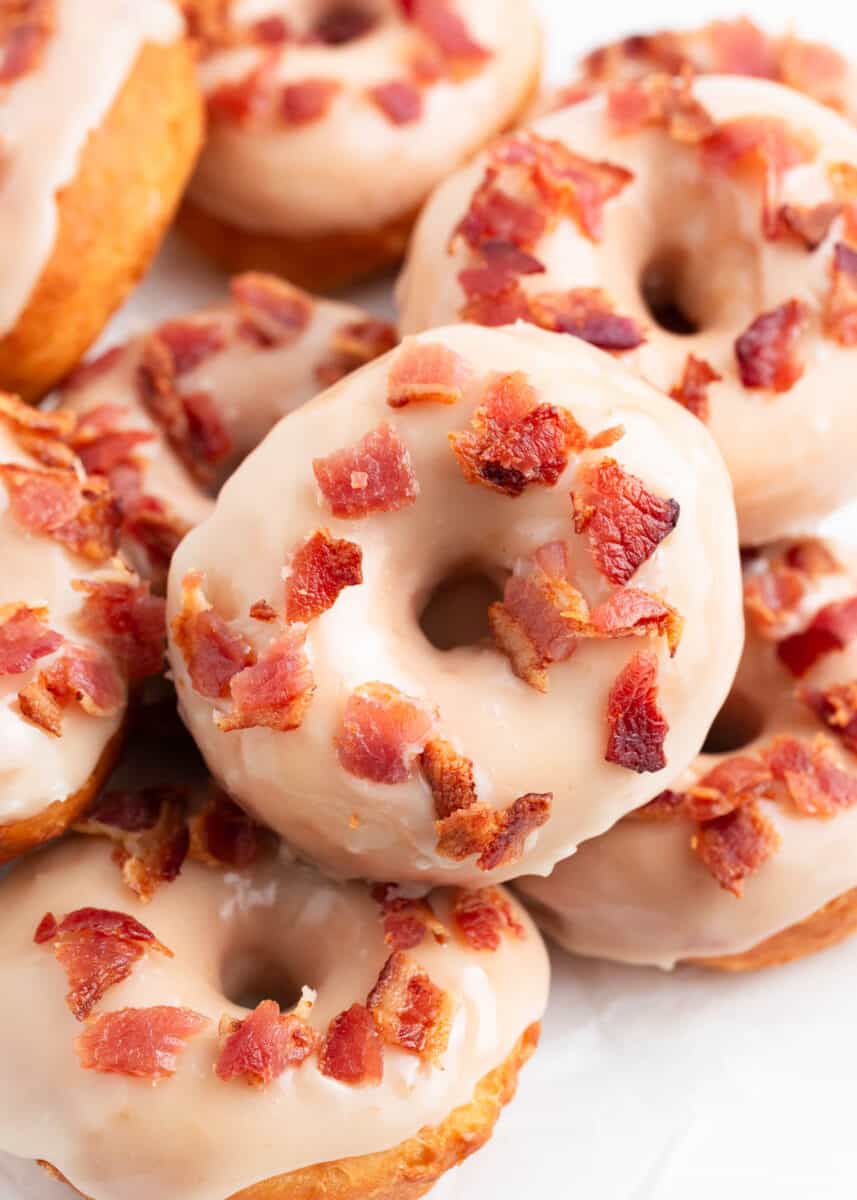 Maple bacon donuts stacked on a plate.