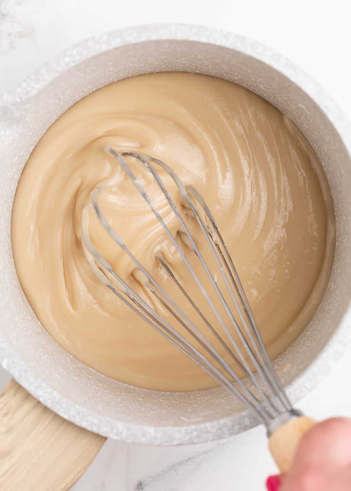 Whisking maple glaze in a grey pot.