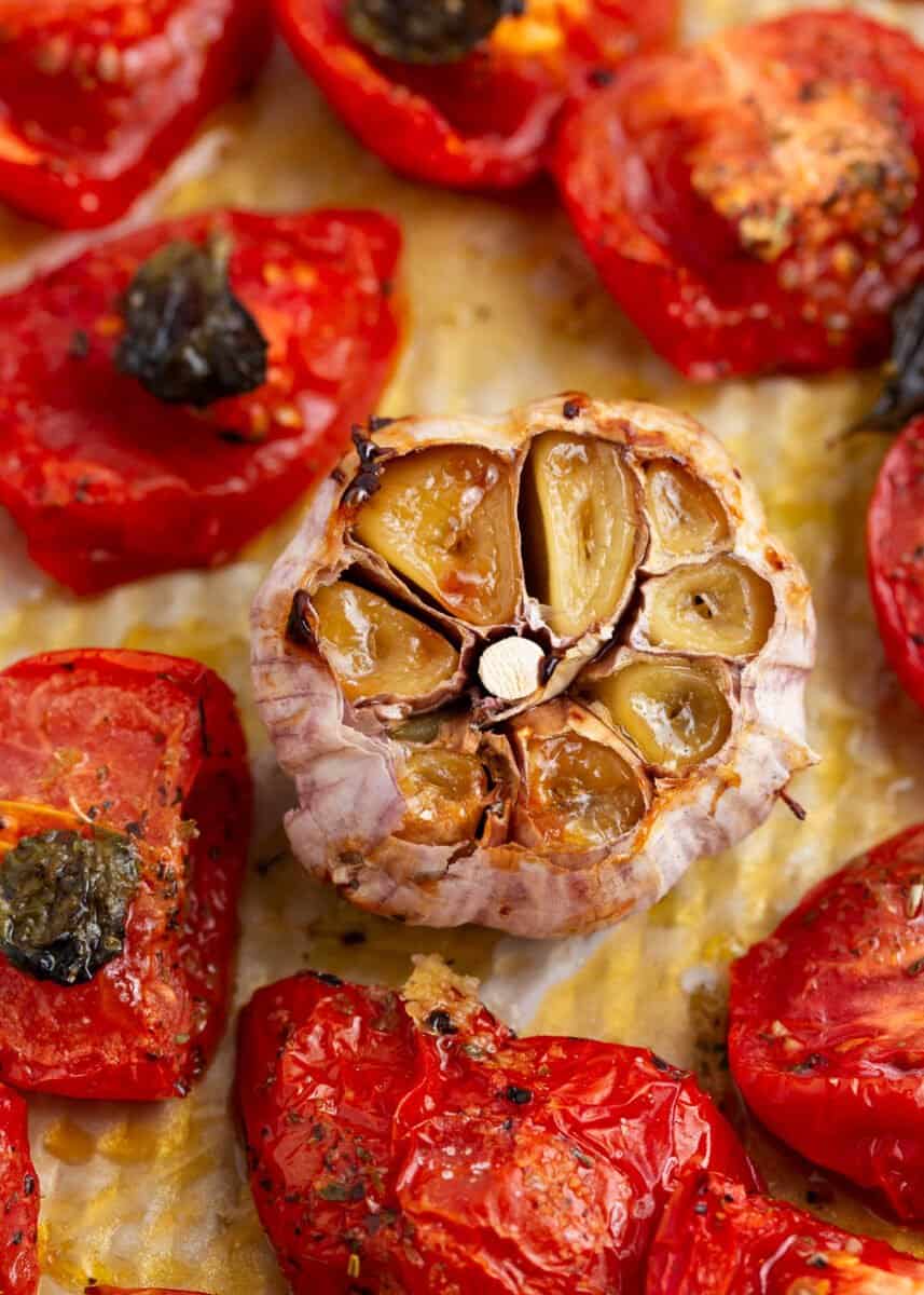 Roasted garlic and tomatoes on baking sheet.