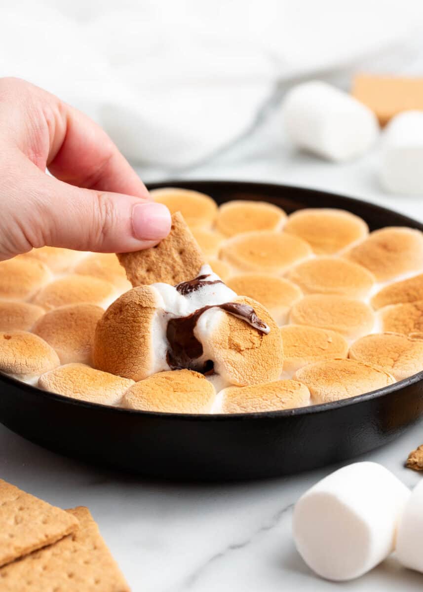 Dipping graham crackers in s'mores dip.