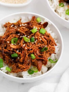 Shredded honey chicken and rice in a white bowl.