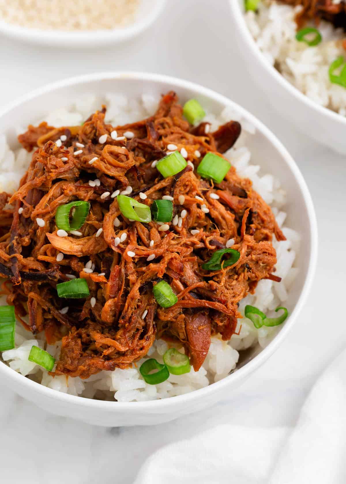 Shredded honey chicken and rice in a white bowl.