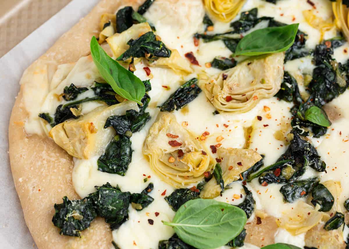 Close up shot of spinach artichoke pizza.
