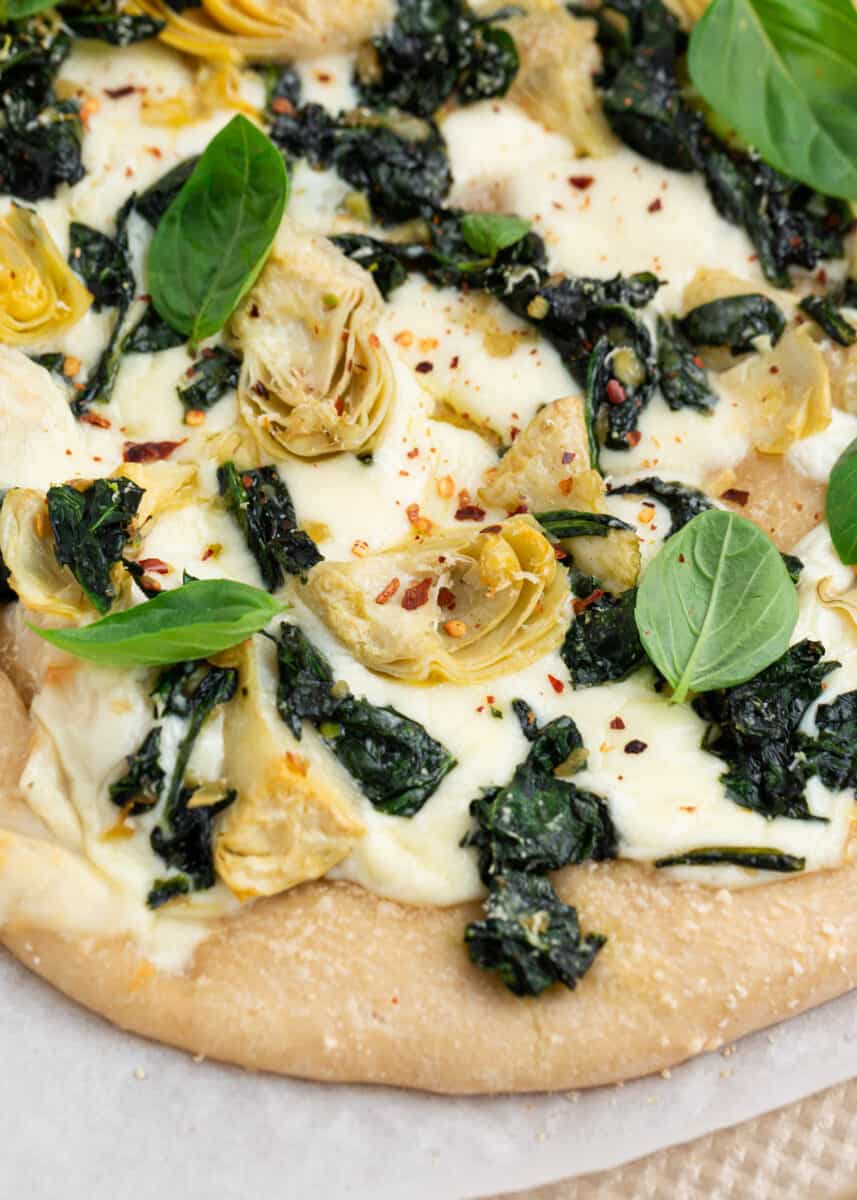 Spinach artichoke pizza with fresh basil on top.
