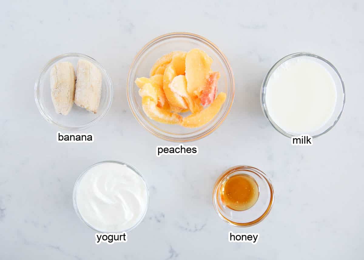 Peach smoothie ingredients on marble counter.