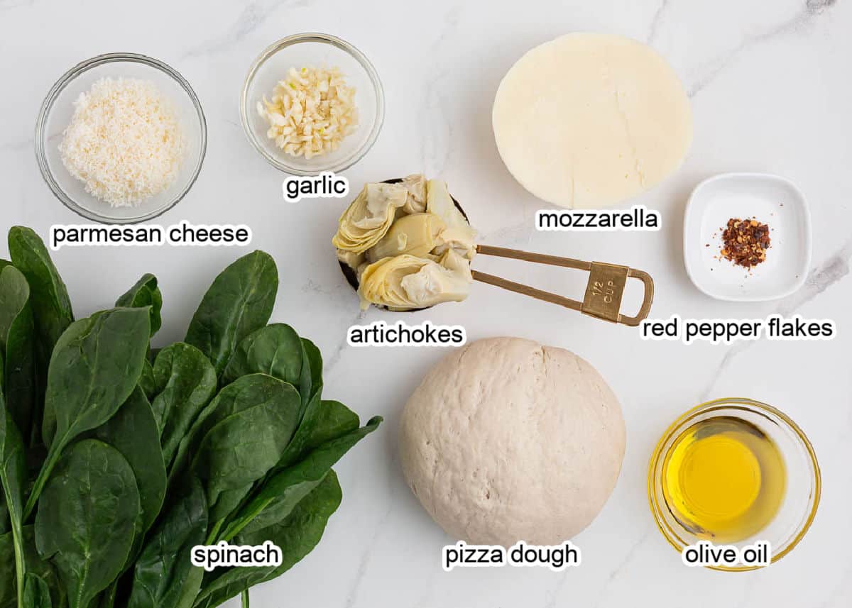 Spinach artichoke pizza ingredients on counter. 
