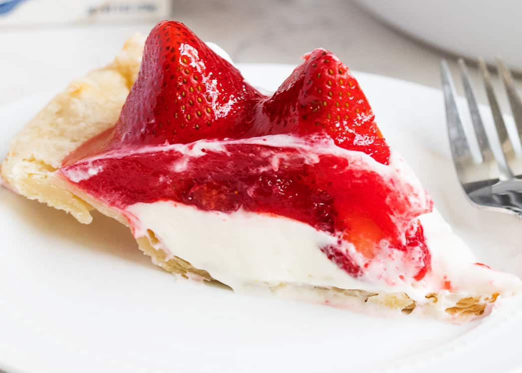 Slice of strawberry cream pie on white plate.