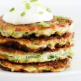 Stack of zucchini fritters on a white plate.