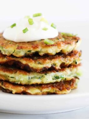 Stack of zucchini fritters on a white plate.
