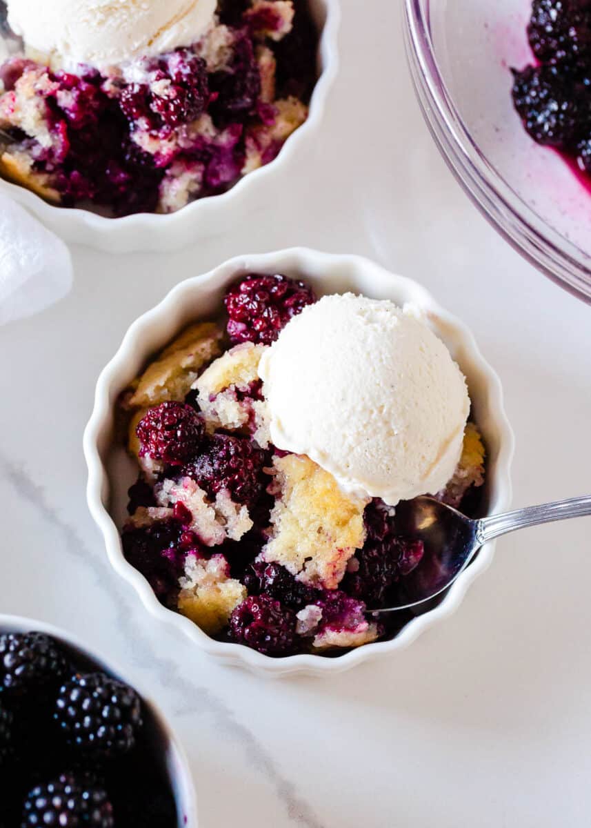 Blackberry cobbler in a white bowl with ice cream. 