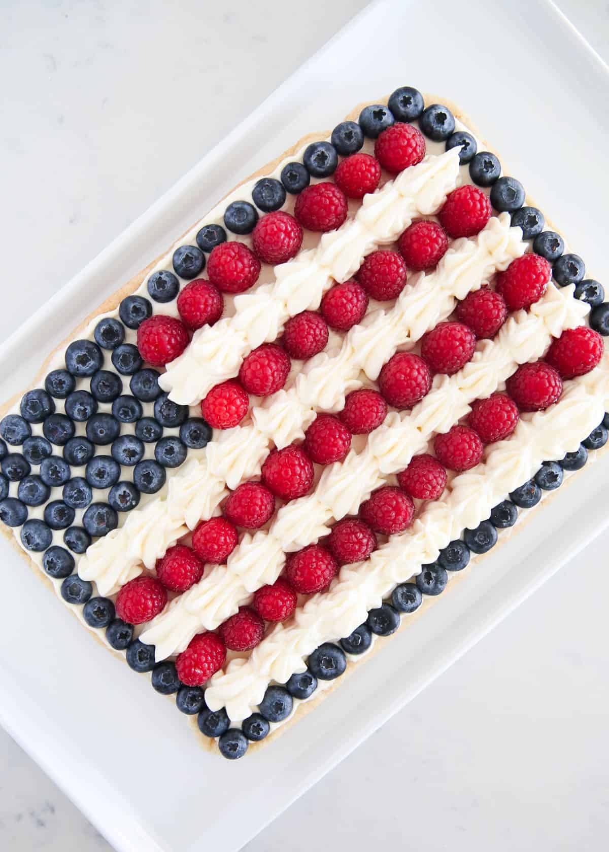 4th of July fruit pizza with berries on white plate.