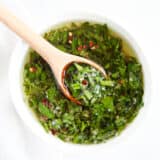 Homemade chimichurri in white bowl with spoon.