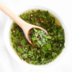Homemade chimichurri in white bowl with spoon.