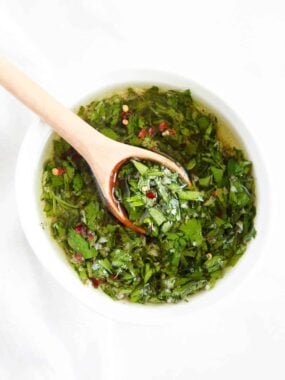 Homemade chimichurri in white bowl with spoon.