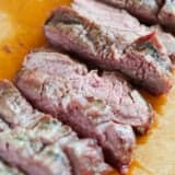 Sliced flank steak on a wooden cutting board.