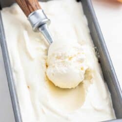 Scooping vanilla ice cream from container.