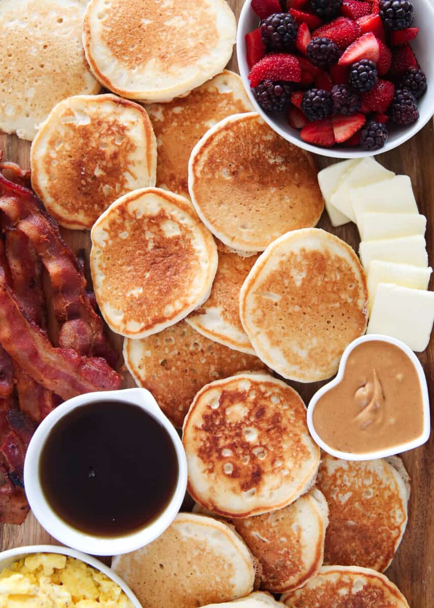 Pancakes and toppings on wooden board.