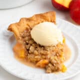 Slice of peach crumble pie with ice cream on top.