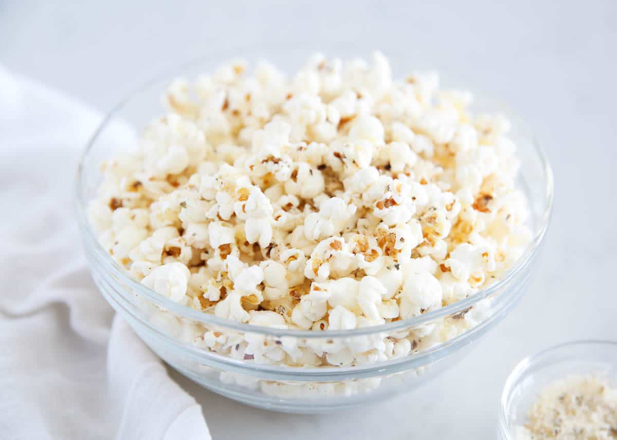 Homemade popcorn with seasoning in a glass bowl.