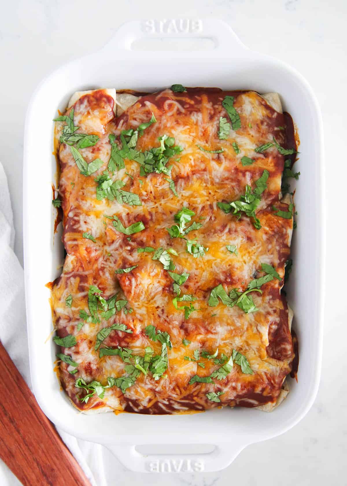 Pork enchiladas in white baking dish.