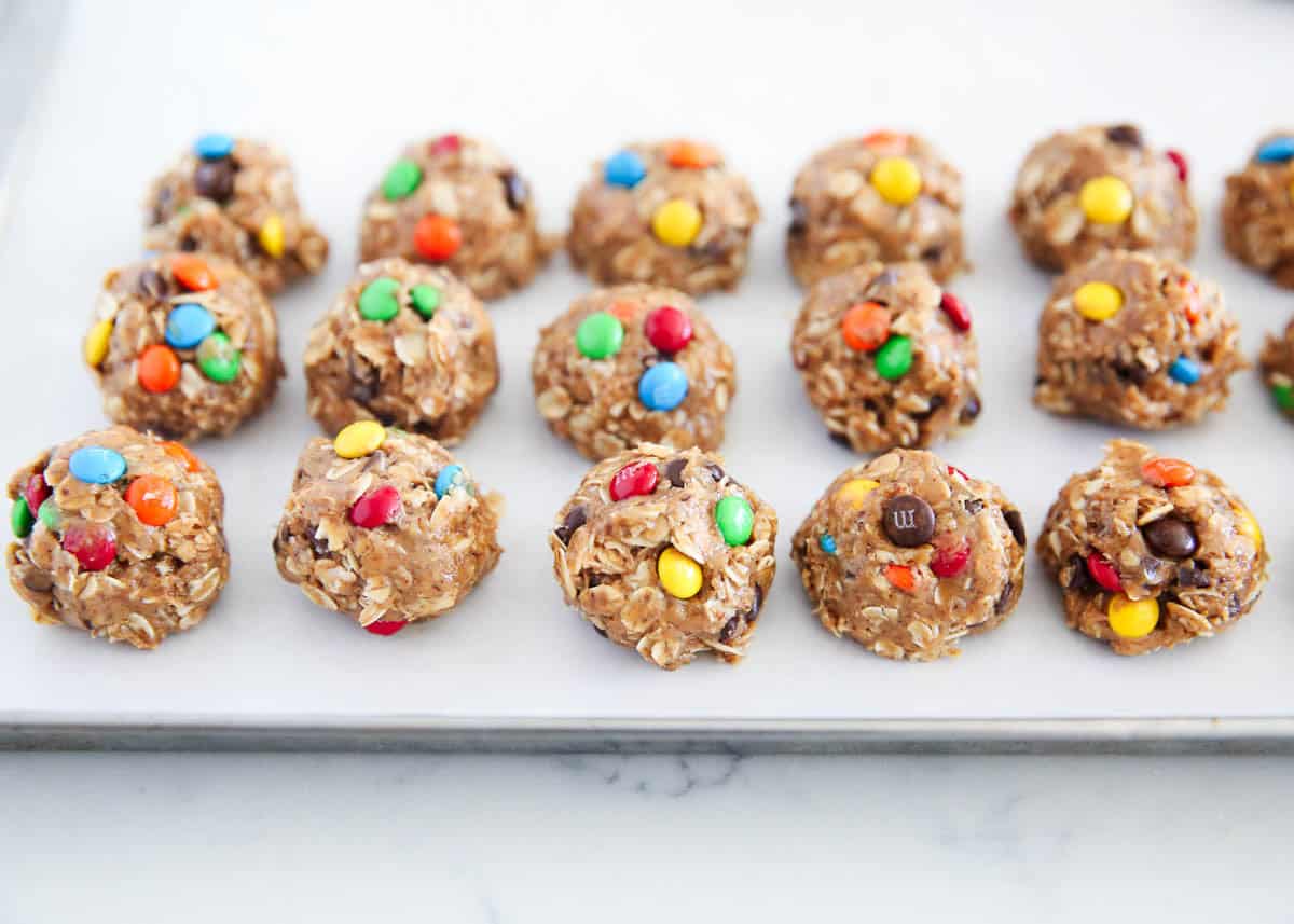 Rolled monster energy balls topped with mini M&Ms on a parchment-lined baking sheet.