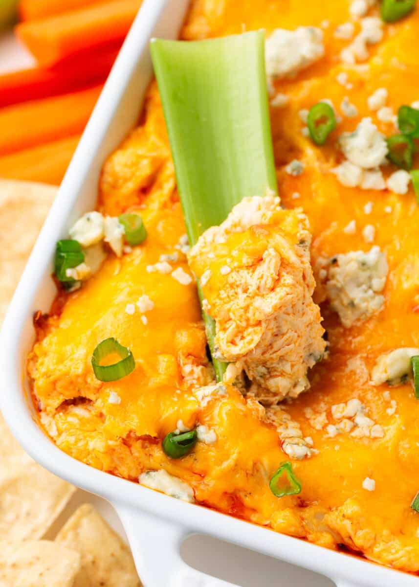 Celery being dipped in buffalo chicken dip.